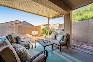 An outdoor patio area with a covered seating area, a pool, and a view of neighboring houses. - Stunning home with pool, patio, grill, central AC & washer/dryer (Peoria)