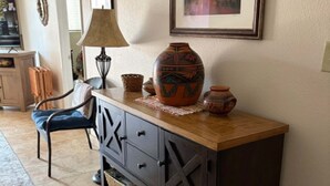 Una habitación con un tocador de madera, una silla, una lámpara y un cuadro en la pared.
