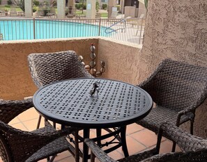 Ein Tisch und Stühle aus Rattan auf einem Balkon mit einem Pool im Hintergrund.
