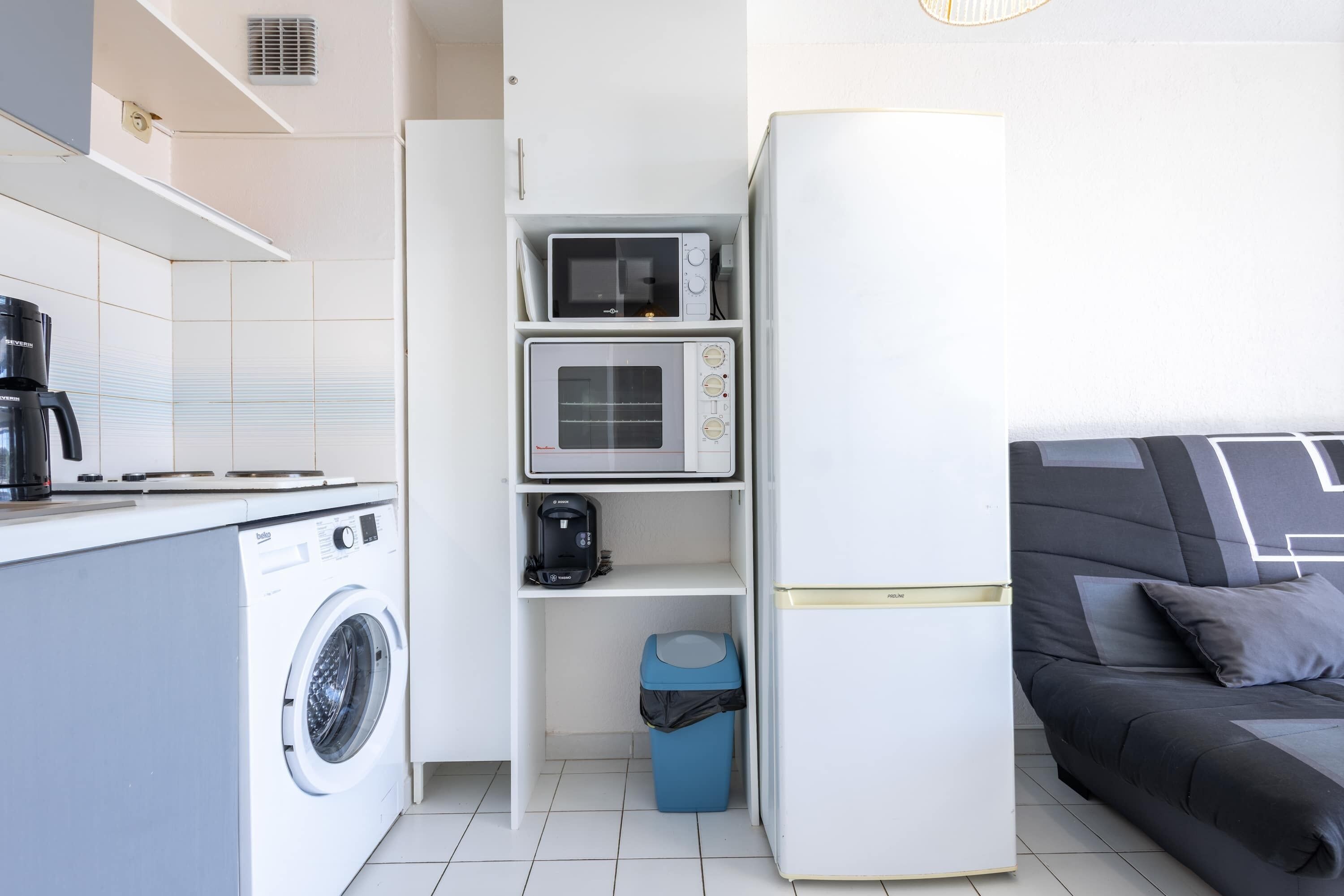 Une petite cuisine équipée comprenant un lave-linge, un four à micro-ondes et une machine à café.