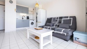 Espai habitable reduït amb petita cuina, un sofà, taula de cafè i moble d'emmagatzematge.