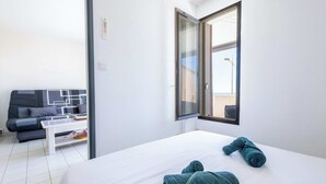Habitació d'hotel amb llit, sofà, taula petita i finestra amb vistes.