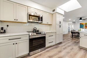 A modern kitchen with white cabinetry, stainless steel appliances, and a herringbone tile backsplash. - Stylish desert oasis with fast WiFi, fenced yard, & screened patio (Scottsdale)