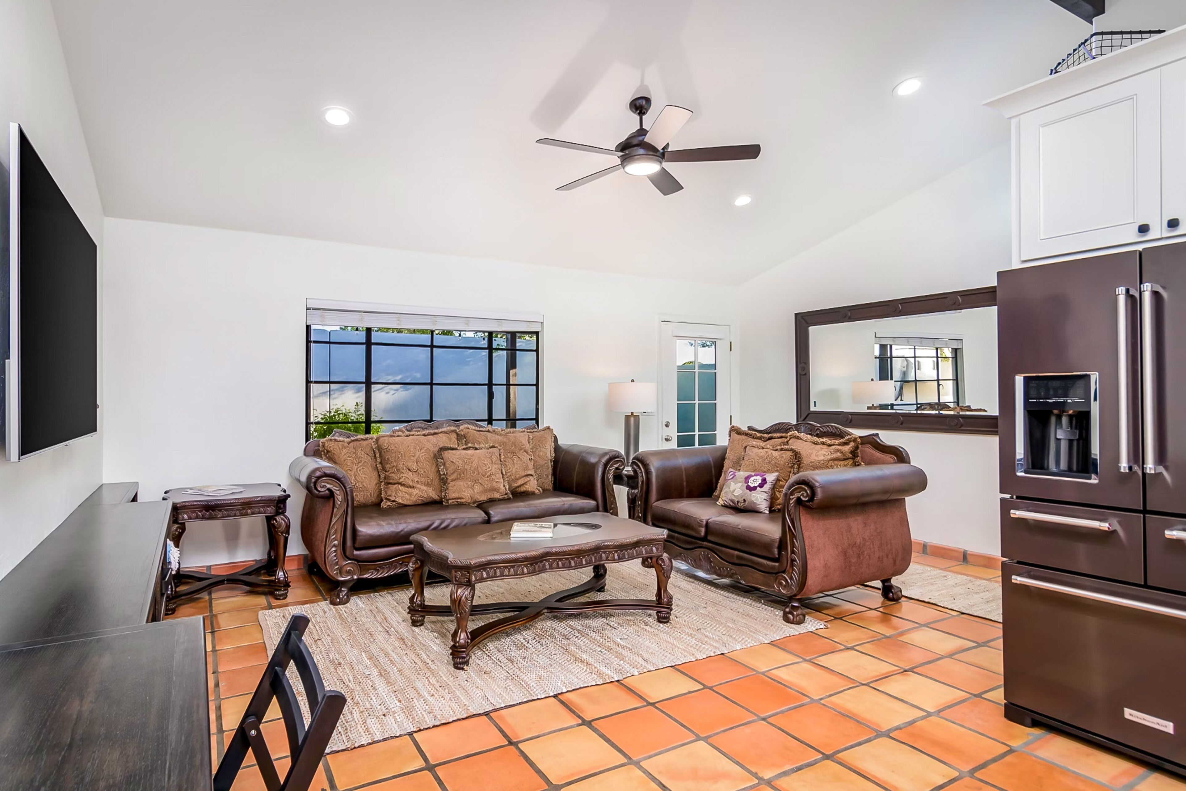 A modern living room with a brown leather sofa, a wooden coffee table, and a ceiling fan.