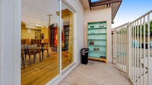 Eine Terrasse mit Glastür zu einem Raum, einem Mülleimer und einem Regal mit Dekoration.