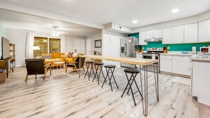 Eine moderne Küche mit weißen Schränken, einem Edelstahl-Kühlschrank und einem Holzespeise-Tisch mit Barhocker.