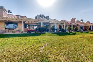 A residential area with multiple houses, a well-maintained lawn, and a clear sky. - Water-view home on golf course with hot tub, pool, tennis, on-site golf, & patio (Palm Desert)
