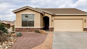 A single-story house with a garage, a stone foundation, and a landscaped front yard with rocks and cacti. - Desert retreat with enclosed yard, instruments, alfresco dining, grill, & W/D (San Tan Valley)