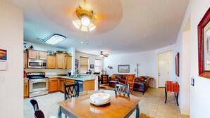 A modern kitchen with a dining area, wooden cabinets, a microwave, and a ceiling fan. - Desert retreat with enclosed yard, instruments, alfresco dining, grill, & W/D (San Tan Valley)