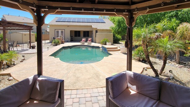 Ein überdachter Außenbereich mit Swimmingpool, Liegestühlen und einer Terrasse mit Topfpflanzen.