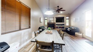 Ein geräumiger Essbereich mit Holztisch und Stühlen, einem Deckenventilator und einem Kamin.