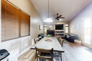 A spacious dining area with a wooden table and chairs, a ceiling fan, and a fireplace. - Spectacular oasis with private pool, large yard, & game room (Surprise)