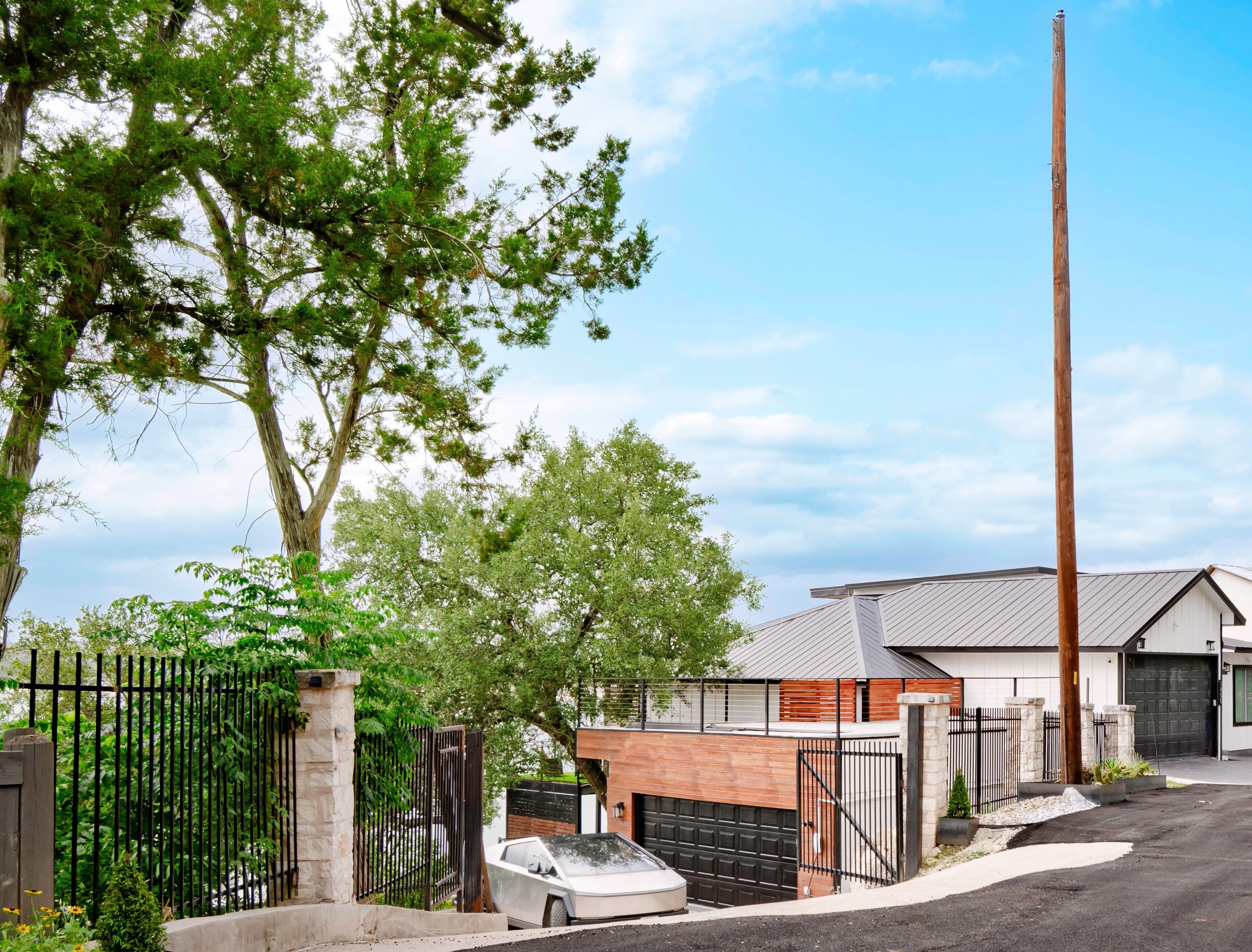 A residential property with a garage, a tall wooden utility pole, and a gated driveway.