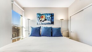 Un dormitorio con una cama grande, un cuadro en la pared y vistas al exterior.