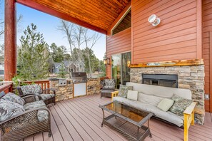 Une terrasse couverte avec des meubles d’extérieur, une cheminée en pierre et un mur en pierre.