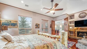 Ein Schlafzimmer mit einem großen Bett, einem Deckenventilator, einem Kamin und einem Fernseher.