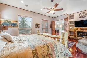 Ein Schlafzimmer mit einem großen Bett, einem Deckenventilator, einem Kamin und einem Fernseher.