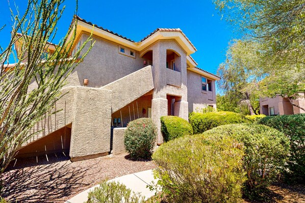 A two-story house with a stone facade, a balcony, and a well-maintained garden. - Vistoso Preserve Casita #220C | Condo in Oro Valley (Oro Valley)
