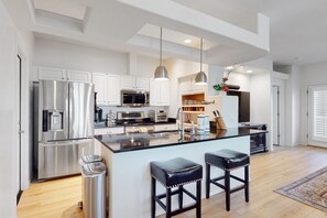 A modern kitchen with stainless steel appliances, white cabinetry, and a central island with bar stools. - Vistoso Preserve Casita #220C | Condo in Oro Valley (Oro Valley)