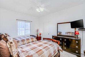 A bedroom with two beds, a dresser, a television, and a window with blinds. - Peaceful, dog-friendly home with private pool, attached spa & patio (Palm Desert)