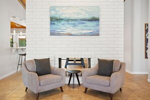 A lobby with two armchairs facing a white brick wall, a painting above the chairs, and a small table between them. - Spacious vacation rental with a private pool, a hot tub & AC (Scottsdale)