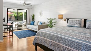 Un dormitorio con cama, escritorio y silla. Se ve un ventanal con vistas al exterior.