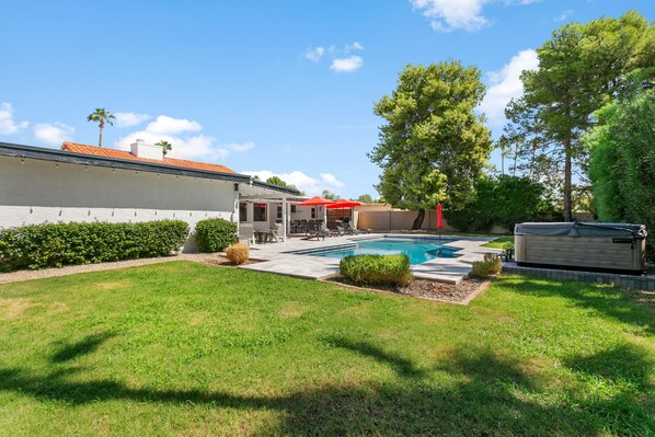 A backyard with a swimming pool, a covered hot tub, and a patio area with outdoor furniture. - Spacious vacation rental with a private pool, a hot tub & AC (Scottsdale)
