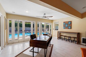 A spacious room with a large dining table, a ceiling fan, and a view of a swimming pool through glass doors. - Relax at this remodeled home & casita w/ private pool & spa - 2 dogs OK (Palm Springs)