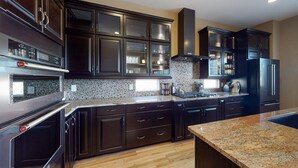 A modern kitchen with dark cabinetry, granite countertops, and stainless steel appliances.