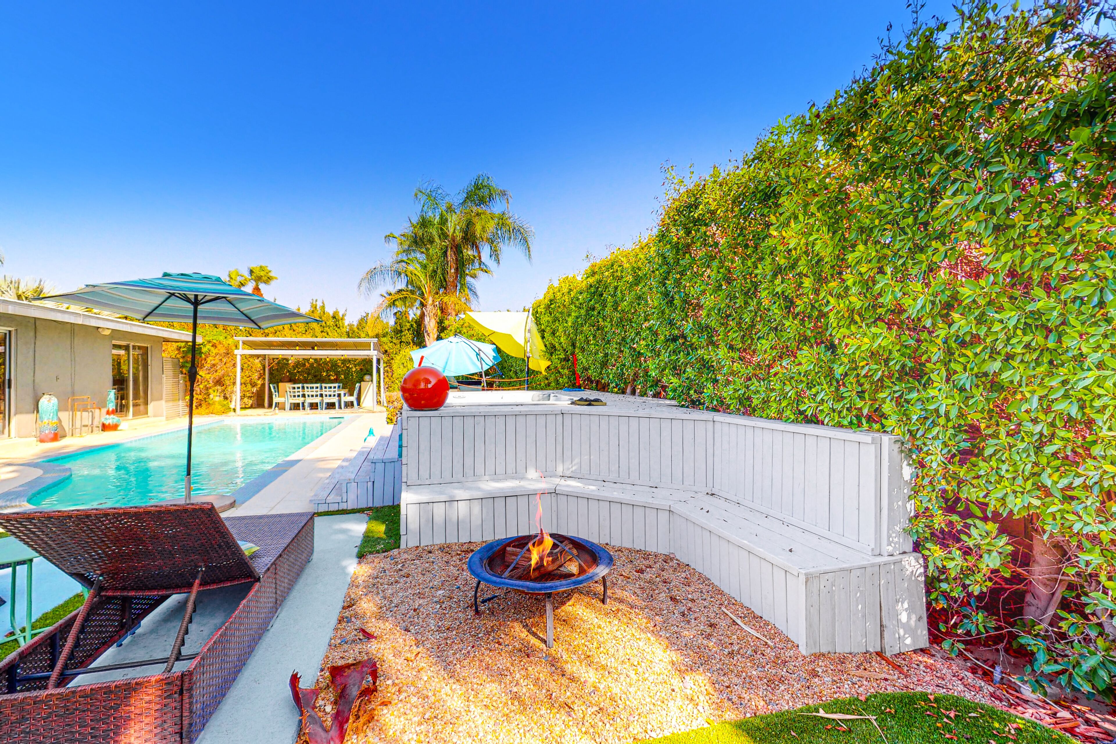 Un patio trasero con piscina, una chimenea y una zona de estar techada.