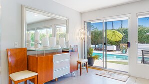 Ein modernes Badezimmer mit einem Glaswaschtisch, einem großen Spiegel und Blick auf einen Pool.