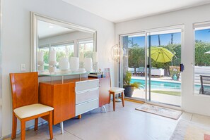 Une salle de bain moderne avec un meuble-lavabo en verre, un grand miroir et une vue sur une piscine.