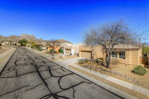 A residential street with houses, a clear blue sky, and a mountain in the background. - Remodeled modern beauty backs to open desert with mountain views & home theatre (Marana)