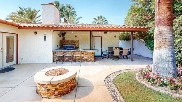 A patio with a fire pit, outdoor seating, and a kitchen area with a bar. - Gorgeous Palm Desert Oasis with Backyard Paradise, Pool, Spa & Private Casita (Palm Desert)