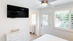 A bedroom with a bed, a dresser, a TV mounted on the wall, a ceiling fan, and a window with blinds. - Gorgeous Palm Desert Oasis with Backyard Paradise, Pool, Spa & Private Casita (Palm Desert)