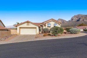 A two-story house with a garage, surrounded by landscaped bushes and a mountain backdrop. - Spacious home with mountain views, grill, central air-conditioning, & free WiFi (Oro Valley)