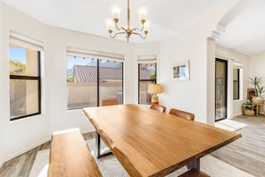 A spacious dining area with a large wooden table, comfortable seating, and a chandelier. - Spacious home with mountain views, grill, central air-conditioning, & free WiFi (Oro Valley)