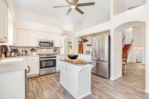 A modern kitchen with white cabinetry, stainless steel appliances, and a wooden island. - Spacious home with mountain views, grill, central air-conditioning, & free WiFi (Oro Valley)