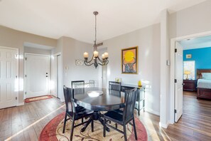 A dining area with a round table, black chairs, and a chandelier. There is a red rug under the table, and a door leading to another room. - Sunny, dog-friendly condo with a heated pool, gym, grilling area, & golf nearby (Oro Valley)
