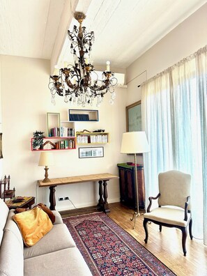 A living room with a chandelier, bookshelves, a sofa, a chair, and a rug. - Elegant & Modern Loft in Torino, Regio Parco (Torino)
