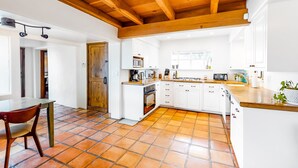 Een moderne keuken met witte kastjes, een houten plafond en een betegelde vloer.