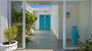 Una entrada moderna a un edificio con puerta de vidrio, una planta en maceta y un jarrón grande.