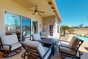 An outdoor patio with a table and chairs, a ceiling fan, and a view of a swimming pool. - Wonderful desert retreat near hiking with private pool, fast WiFi & gas grill (Oro Valley)