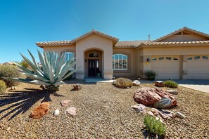 A house with a beige facade, a tiled roof, and a front entrance with a door and windows. - Wonderful desert retreat near hiking with private pool, fast WiFi & gas grill (Oro Valley)