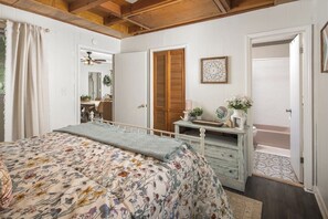 Ein Schlafzimmer mit einem Bett, einem Schminktisch, einem Spiegel und einer Tür zu einem Badezimmer.