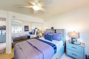 Ein Schlafzimmer mit zwei Betten, einem Deckenventilator, Nachttischlampen und einem Nachttisch mit Lampe.
