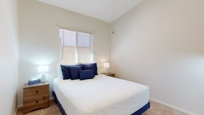 A bedroom with a bed, bedside lamps, a nightstand, and a window with blinds. - Dog-friendly desert home with mountain views, enclosed yard, grill, W/D, and AC (Oro Valley)