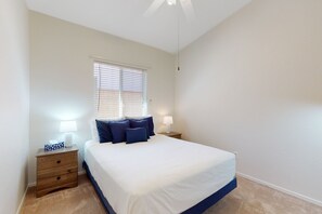 A bedroom with a bed, bedside lamps, a nightstand, and a window with blinds. - Dog-friendly desert home with mountain views, enclosed yard, grill, W/D, and AC (Oro Valley)
