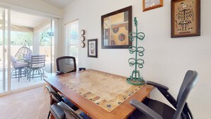 A dining area with a wooden table, chairs, and a view of the outdoors. - Dog-friendly desert home with mountain views, enclosed yard, grill, W/D, and AC (Oro Valley)