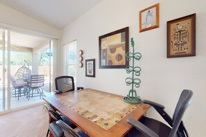 A dining area with a wooden table, chairs, and a view of the outdoors. - Dog-friendly desert home with mountain views, enclosed yard, grill, W/D, and AC (Oro Valley)